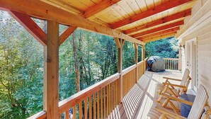 A wooden deck with a railing, wooden chairs, and a view of a forest. - Smoky View Retreat (Maggie Valley)