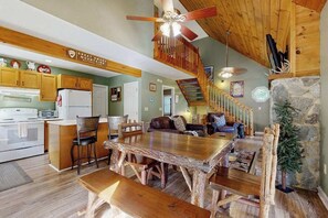 Ein rustikales Interieur mit einem Holzespeisetisch, einer Küchenzeile und einer Treppe, die zu einer weiteren Ebene führt.