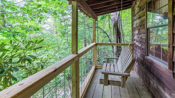 A wooden deck with a bench, surrounded by trees. - The Outpost (Whittier)