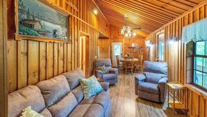 A wooden interior with a sofa, armchairs, a dining table, and a painting on the wall. - The Outpost (Whittier)