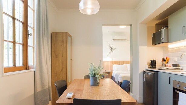 A modern kitchen with a wooden dining table, chairs, and a built-in oven. - EmilioVaisse Apartments by Andes STR (Providencia)