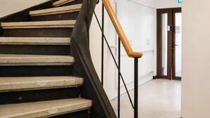 A staircase with black railings and wooden handrails, leading to a room with white walls and a door. - EmilioVaisse Apartments by Andes STR (Providencia)