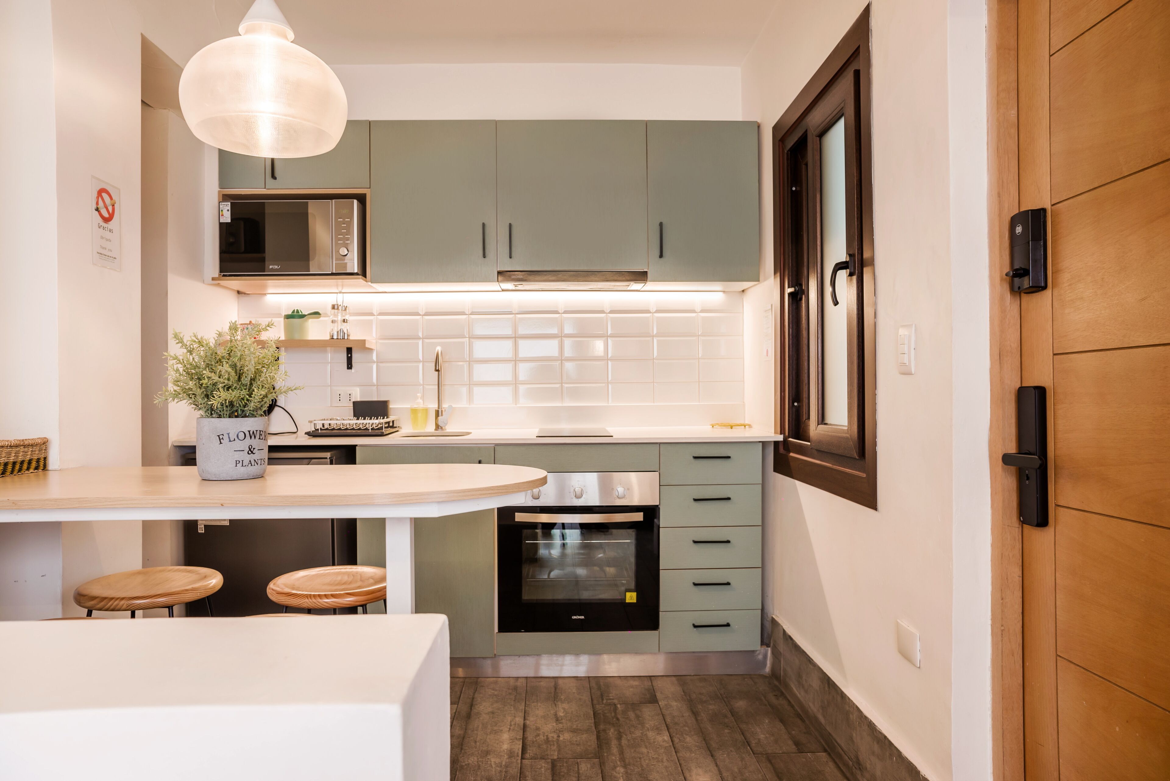 A modern kitchen with a microwave, oven, and green cabinets.