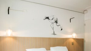 A bedroom with a bed, wooden headboard, wall-mounted light fixtures, and a wall art of a flamingo. - EmilioVaisse Apartments by Andes STR (Providencia)