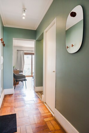 A hallway with wooden flooring, a white door, a mirror, and a view to a balcony. - EmilioVaisse Apartments by Andes STR (Providencia)
