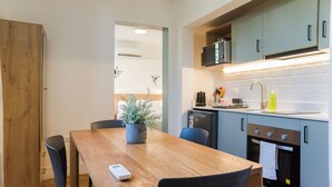 A compact kitchen with a wooden table, chairs, a microwave, and a dishwasher. - EmilioVaisse Apartments by Andes STR (Providencia)