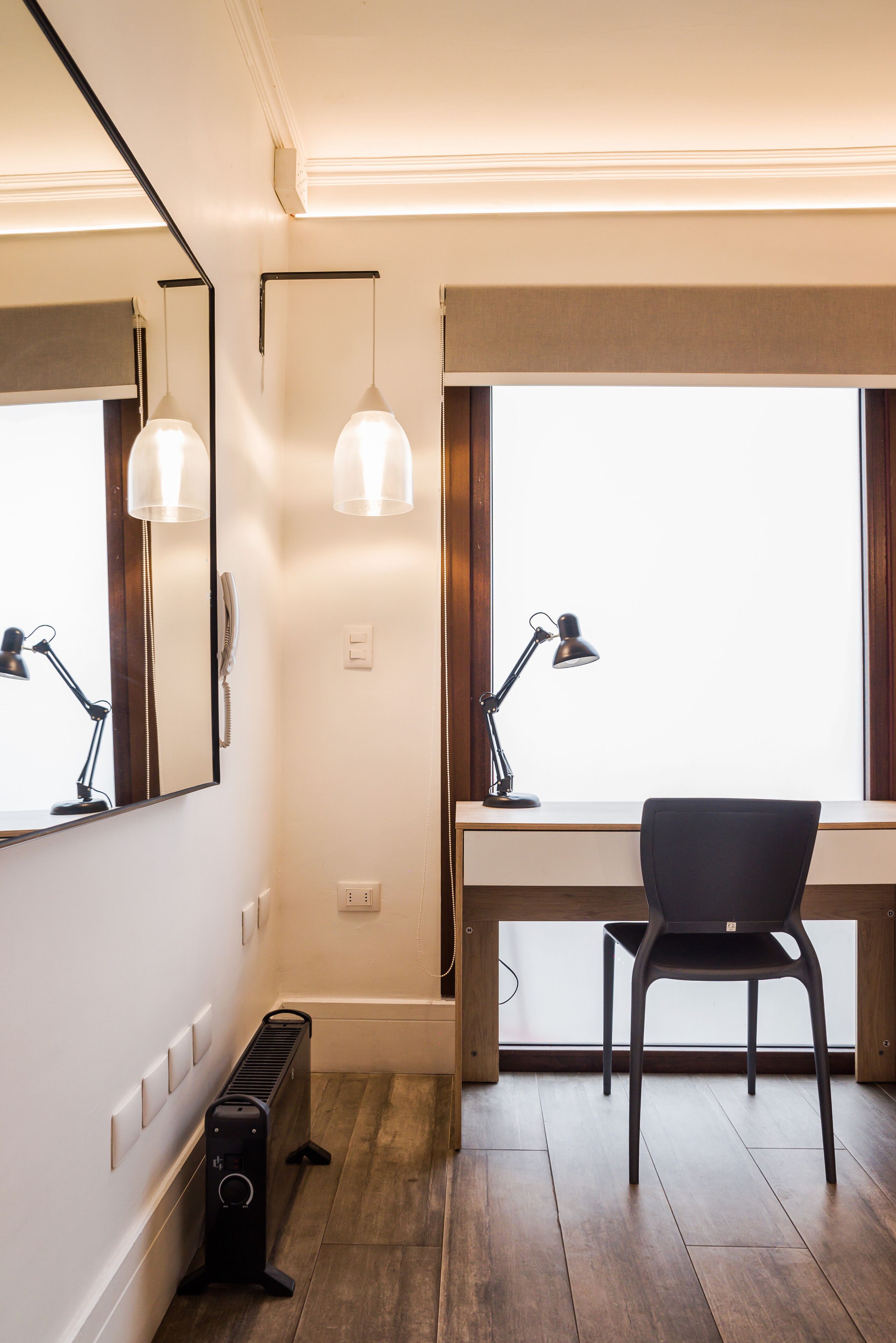 Een moderne kantoorruimte met een bureau, twee lampen, een stoel en een groot raam.