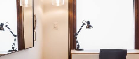 Un espacio de oficina moderno con un escritorio, dos lámparas, una silla y un ventanal grande.