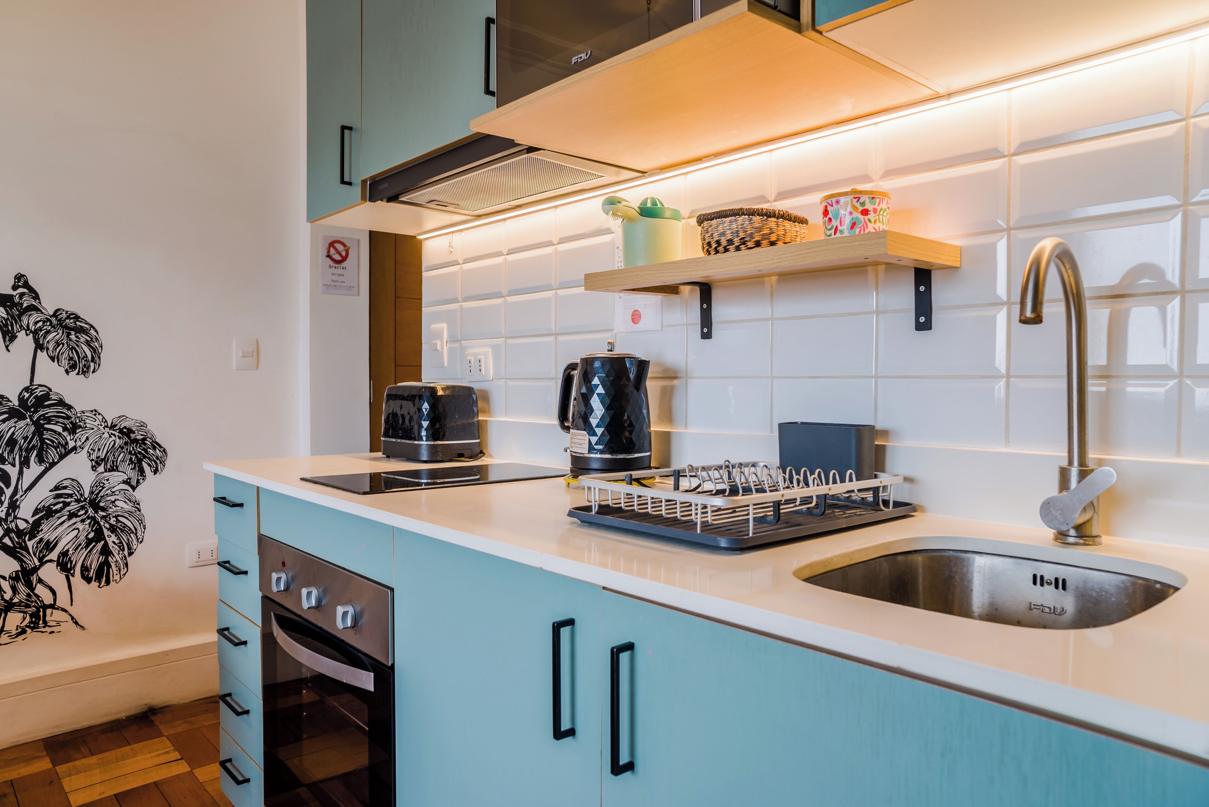 A modern kitchen with a built-in oven, a coffee maker, and a sink.