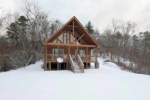 Eine Holzhütte mit einem Balkon, einer Treppe und Blick auf den umliegenden Wald.