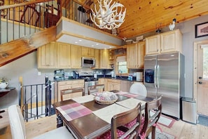 L’intérieur d’un chalet en bois comprend une cuisine, un coin repas et un escalier.