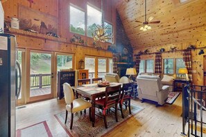 L’intérieur d’une cabane en rondins comprend un coin repas, un canapé et une cheminée.