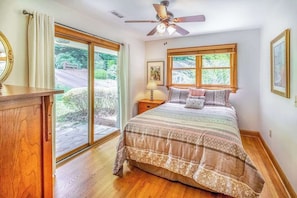 A bedroom with a bed, a ceiling fan, a nightstand, a lamp, and a window. - Secluded Dog-Friendly Home w/Spacious Deck, Gas Grill, Gas Fireplace, Fast WiFi (Waynesville)