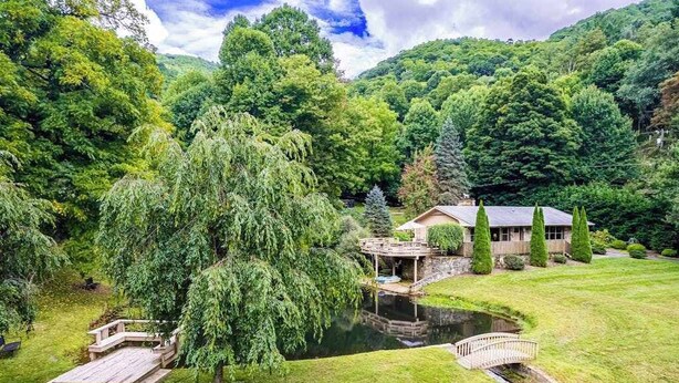A house with a pond, wooden deck, and a bridge. - The Rock House at Big Bear Estates (Waynesville)
