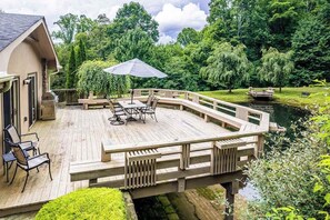 A wooden deck with outdoor furniture, a small boat, and lush greenery. - Secluded Dog-Friendly Home w/Spacious Deck, Gas Grill, Gas Fireplace, Fast WiFi (Waynesville)