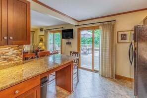 Una cocina con encimera de granito, armarios de madera, lavavajillas integrado y un amplio ventanal que da a un patio exterior.