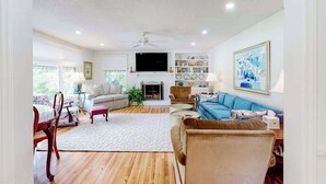 Una sala de estar con chimenea, televisor y estantería.