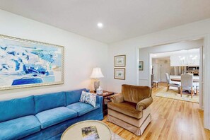 A living room with a blue sofa, a brown armchair, a round coffee table, and a painting on the wall. - Blue Ridge Cottage (Waynesville)
