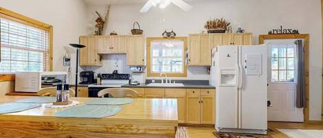 A kitchen with wooden cabinets, a white refrigerator, a ceiling fan, and a dining area with a wooden table and chairs.