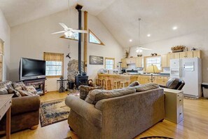 A spacious living room with a large sofa, a television, and a fireplace. - Carrie’s Cabin (Sylva)