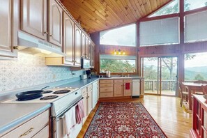 A kitchen with a stove, cabinets, and a large window.