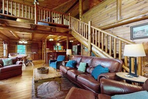 Ein rustikales Blockhaus-Interieur mit Treppe, Ledersofa und Holzdielen.