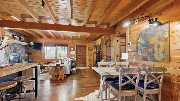 A log cabin interior with a kitchen, dining area, and a fireplace. - Bear Hug (Sylva)