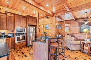 A wooden cabin interior with a kitchen, bar area, and seating. - Timberwolf (Tuckasegee)