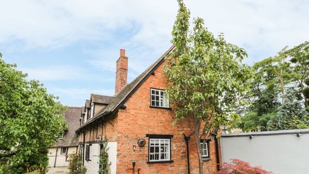 A traditional brick house with a stone pathway, a table, and chairs outside. - 4 Masons Court (Stratford-upon-Avon)