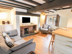Una sala de estar acogedora con chimenea, un sofá, una mesa de comedor y una encimera de cocina.