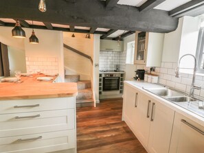Eine moderne Küche mit weißen Schränken, einer Holz Arbeitsplatte und einem eingebauten Backofen.