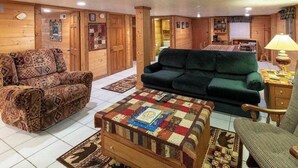 Una sala acogedora con un sofá estampado, un sofá verde y una mesa de centro acolchada.