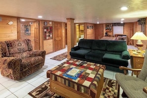 A cozy living room with a patterned sofa, a green couch, and a quilted coffee table. - Meadowbrook Log Cabin (Bryson City)