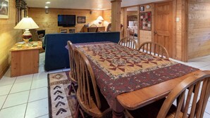 Un interior de madera con una mesa de comedor, sillas, un sofá y un televisor.