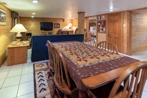 A wooden interior with a dining table, chairs, a sofa, and a TV. - Meadowbrook Log Cabin (Bryson City)