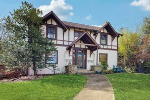 Ein traditionelles Fachwerkhäuschen mit Veranda, Steinuntergrund und gepflegtem Rasen.