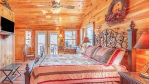 Una camera da letto accogliente in legno, con un letto, una panca, un comò e un televisore.