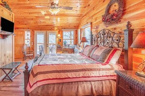Ein gemütliches Schlafzimmer in einer Blockhütte mit Bett, einer Bank, einem Schminktisch und einem Fernseher.