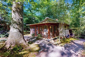 Eine Hütte mit Veranda, umgeben von Bäumen.