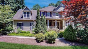 A two-story house with a front porch, a driveway, and a well-maintained lawn. - Expansive Designer Estate w/ TV Room, Spacious Kitchen & Large Yard dog friendly (Arden)