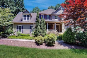 A two-story house with a front porch, a driveway, and a well-maintained lawn. - Expansive Designer Estate w/ TV Room, Spacious Kitchen & Large Yard dog friendly (Arden)