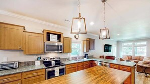 Una cocina con armarios de madera, un refrigerador de acero inoxidable, un microondas, una estufa y una isla de madera.