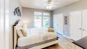 Un dormitorio con cama, ventilador de techo, ventana y puerta.