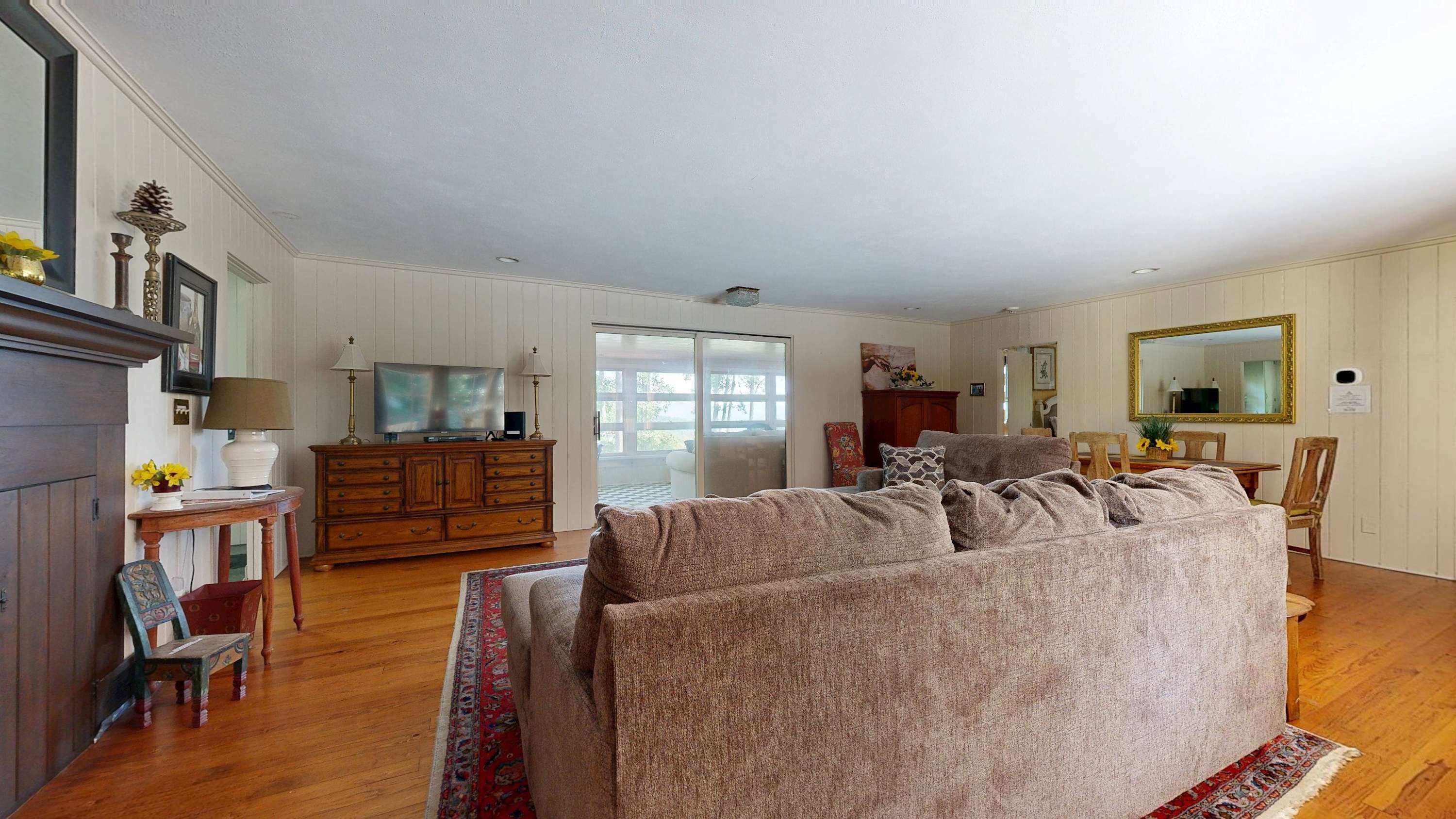 A spacious living room with a large sofa, a television, and a dining area with a table and chairs.