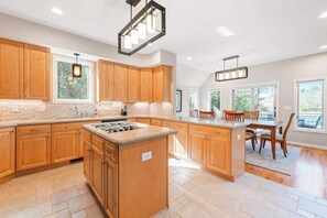 Una cocina amplia con armarios de madera, una isla central y un comedor con sillas.