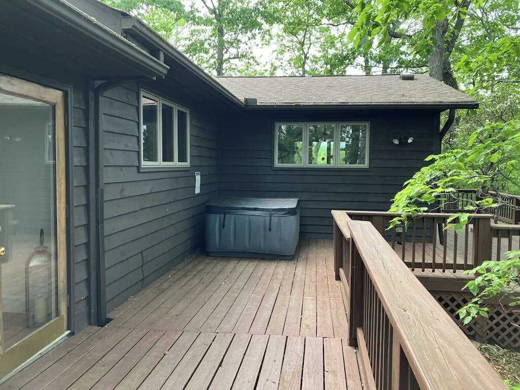 Eine Holzterrasse mit Whirlpool, überdachter Sitzgruppe und Holzgeländer.