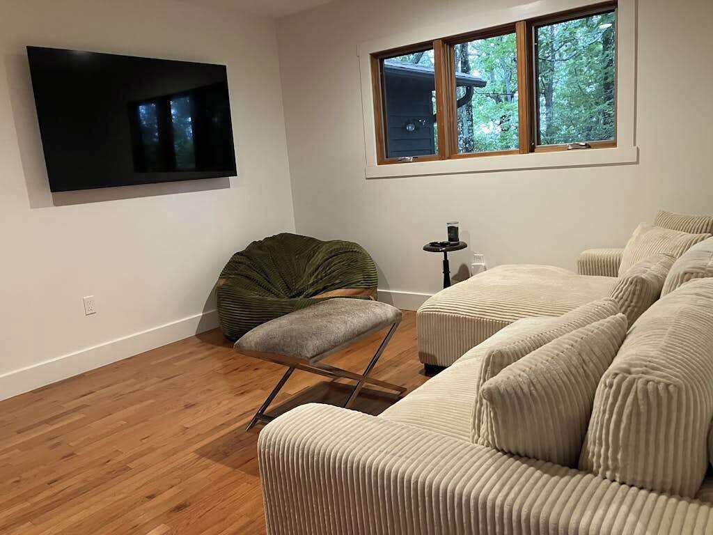 A living room with a flat-screen TV, a bean bag chair, a small table with a lamp, and a sofa.