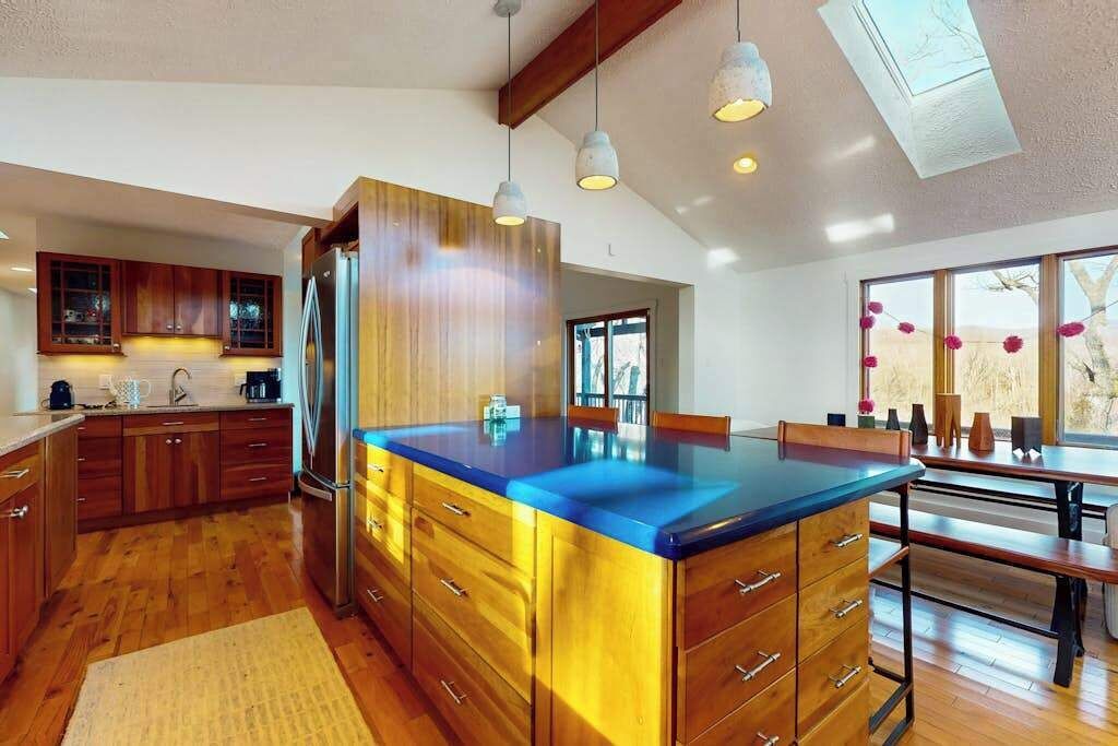 Una cocina moderna con armarios de madera, encimera azul e iluminación colgante.