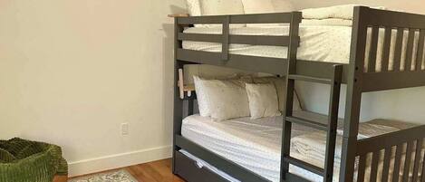 A bunk bed with a wooden frame, a grey floor, and a patterned rug.