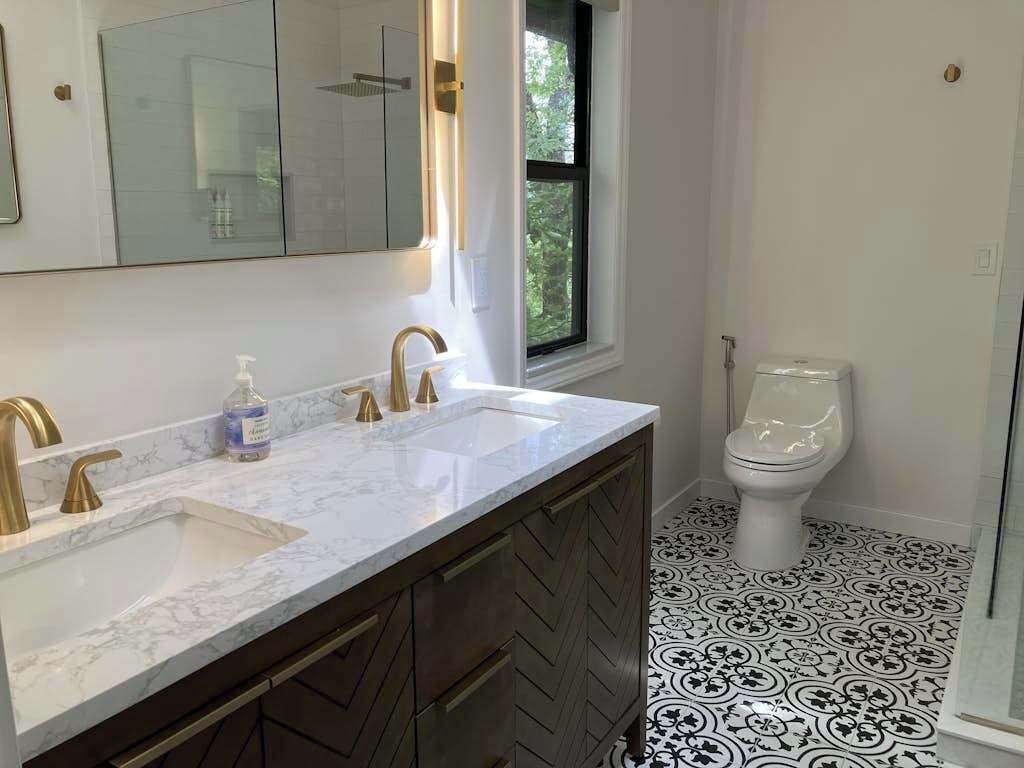 Un baño con lavamanos doble, inodoro y ventana.